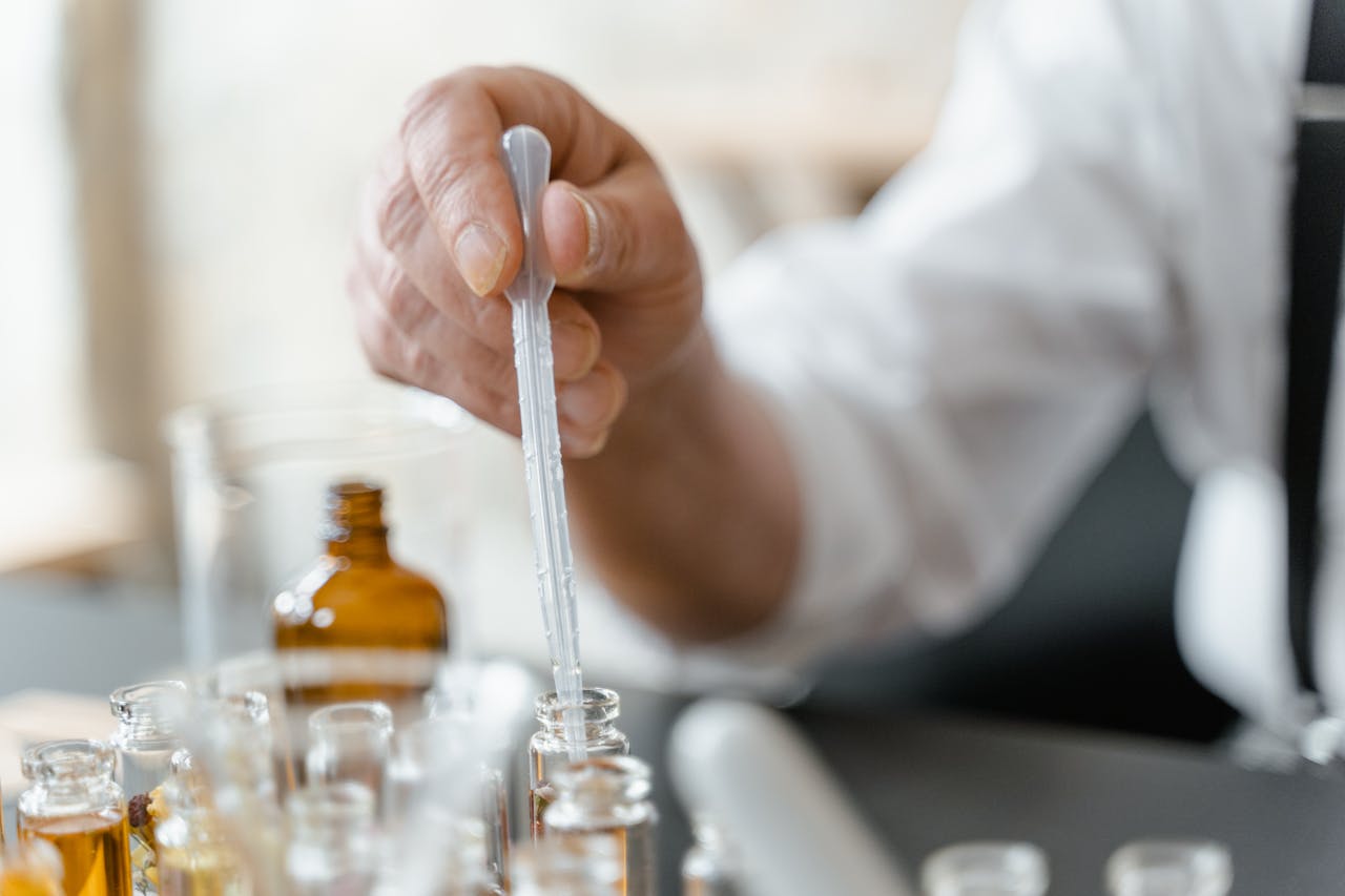 Detailed image of a person mixing essential oils in a laboratory setting.